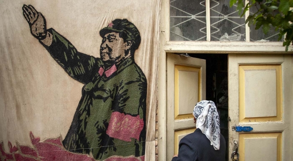 마오쩌둥 그림 앞에 있는 위구르족 여성